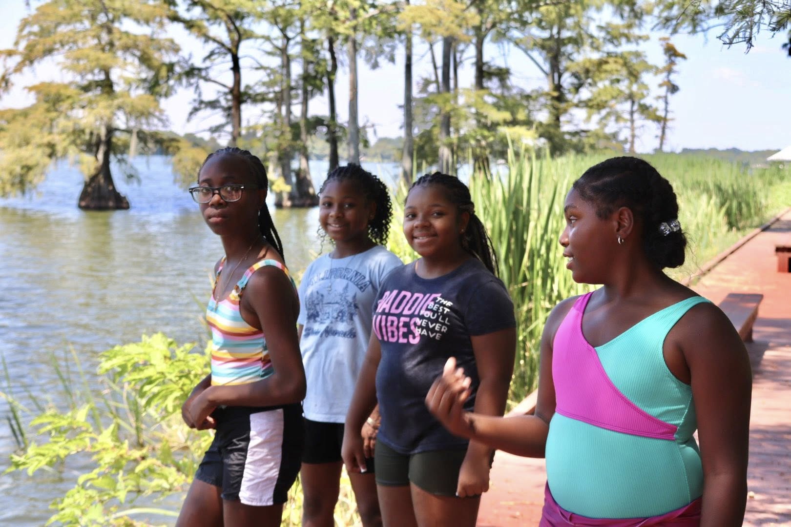 Four girls posing for a photo beside a lake.